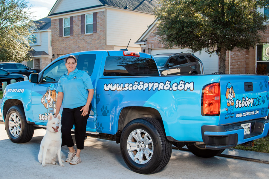 Scoopy Pro technician with dog in front of branded truck at residential home